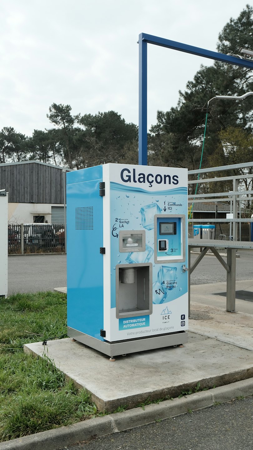 An automated ice vending machine sits on a concrete pad.